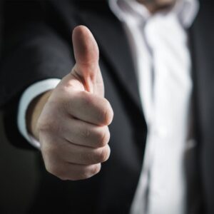 A close-up of a man's thumbs up gesture, symbolizing success and agreement.