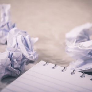 Crumpled papers scattered around a notepad, symbolizing creative process and ideas.