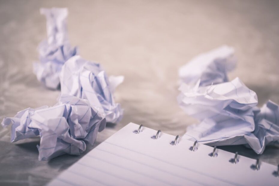 Crumpled papers scattered around a notepad, symbolizing creative process and ideas.